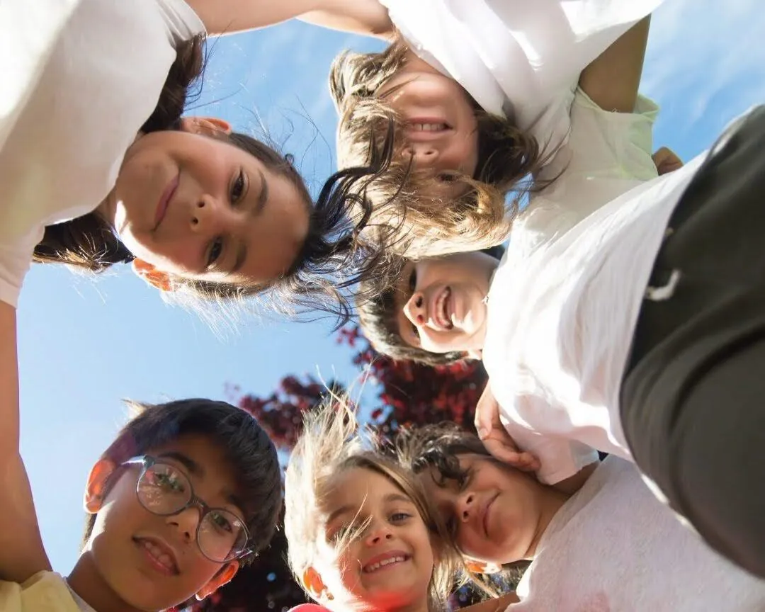 Grupo de niños sonriendo en círculo en el parque Rayo Inflables